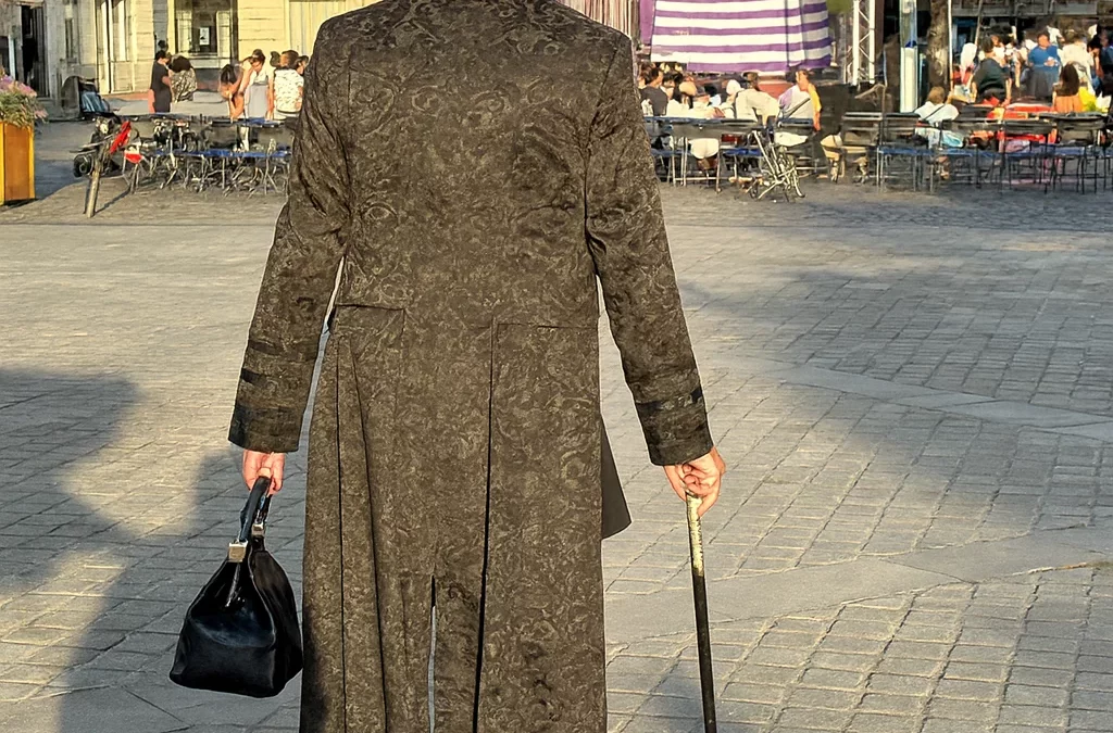 Ambros Varius de dos, tenant une canne et un doctor bag, lors d'un événement à Tours.